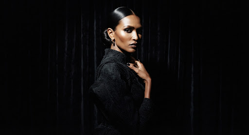 High-fashion portrait of a model in a dimly lit studio, harsh spotlight illuminating the face, deep velvet background, luxury editorial style.